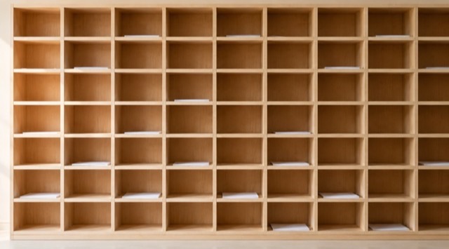 Course cover AI in Administration: wall of many equally sized, unlabelled pigeonholes made of light wood (AI generated)